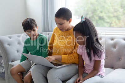 Mother and children using laptop on a sofa in living room