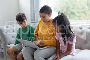 Mother and children using laptop on a sofa in living room