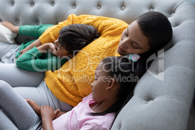 Mother and children sleeping together on a sofa in living room