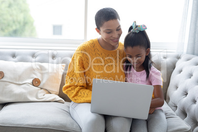 Mother and daughter using laptop on a sofa in living room