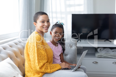 Mother and daughter using laptop on a sofa in living room