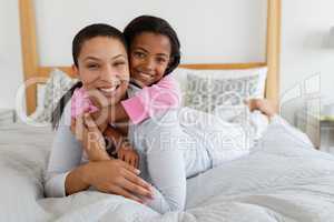 Mother and daughter embracing each other in bedroom at home