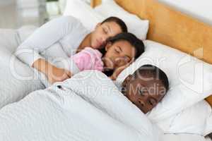 Mother and children sleeping together in bed in bedroom