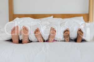 Mother and children sleeping barefoot in bed in bedroom at home
