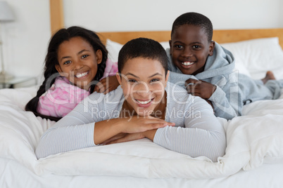 Mother and children relaxing together on bed in bedroom at home Mother and children relaxing together on bed in bedroom at home