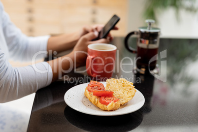 Woman using mobile phone on a table at kitchen