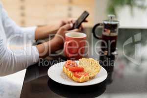 Woman using mobile phone on a table at kitchen