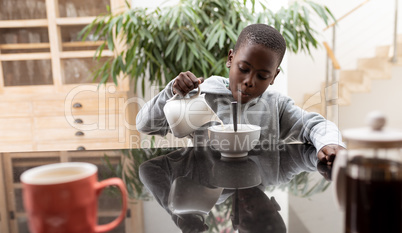 Boy pouring milk in a bowl on dining table