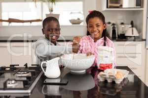 Siblings preparing food on a dining table in kitchen at home