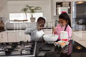 Siblings preparing food on a dining table in kitchen at home