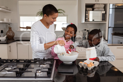 Mother and children preparing food on a worktop in kitchen