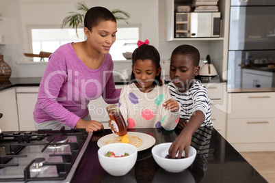 Mother and children preparing food on a worktop in kitchen