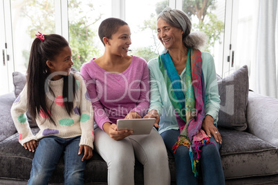 Multi-generation family using digital tablet on a sofa in living room