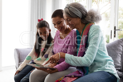 Multi-generation family using digital tablet on a sofa in living room