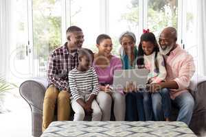 Multi-generation family using laptop on a sofa in living room