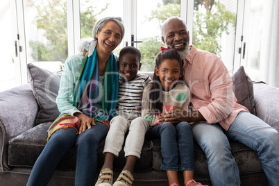 Multi-generation family relaxing together on a sofa in living room at home