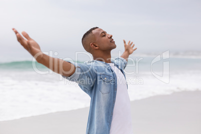 Man standing with arms outstretched on the beach