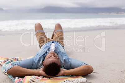 Man sleeping with hands behind head at beach