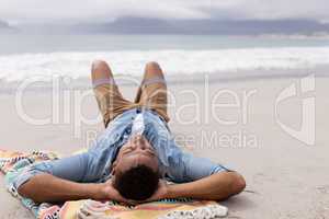 Man sleeping with hands behind head at beach