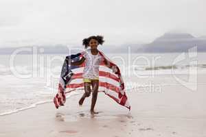 Girl running with American flag on the beach