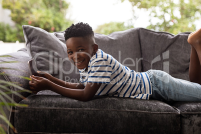 Boy using digital tablet on a sofa in living room at home