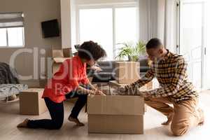 Couple unpacking cardboard boxes in living room