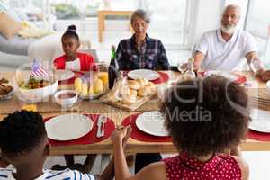Multi-generation family praying before having meal on dining table