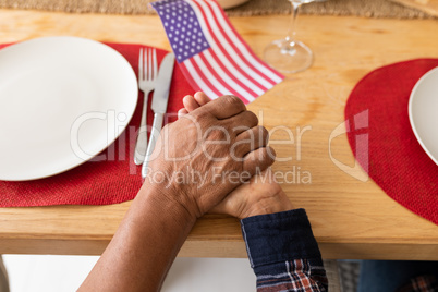 Senior couple praying with hand in hand on dining table at home