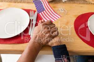 Senior couple praying with hand in hand on dining table at home