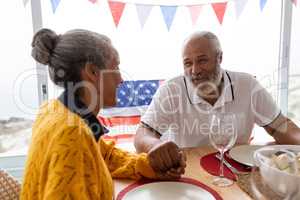 Senior man holding hands of senior woman while having meal on a dining table