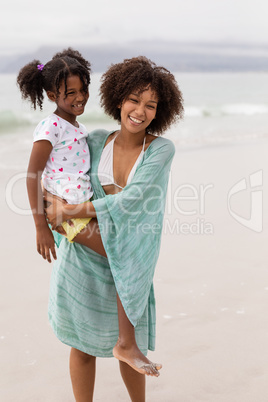 Mother and daughter standing together at beach on a sunny day