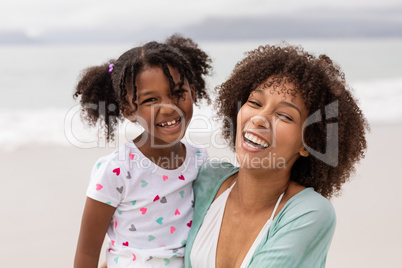 Mother and daughter standing together at beach on a sunny day