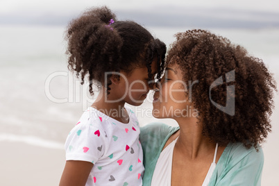 Mother and daughter rubbing noses at beach on a sunny day