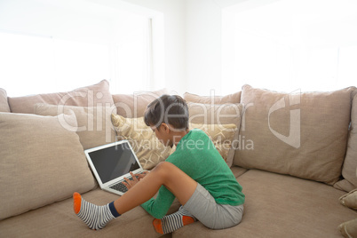 Boy using laptop on sofa at home