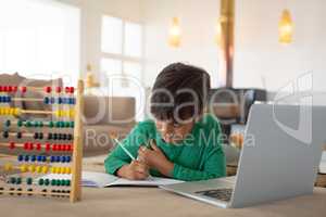 Boy using laptop while studying in living room at home