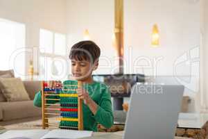 Boy learning mathematics with abacus in a comfortable home