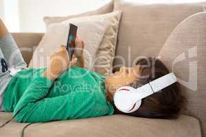 Boy with headset playing game on mobile phone on sofa in a comfortable home