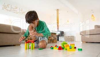 Boy playing with building blocks on floor in living room at comfortable home