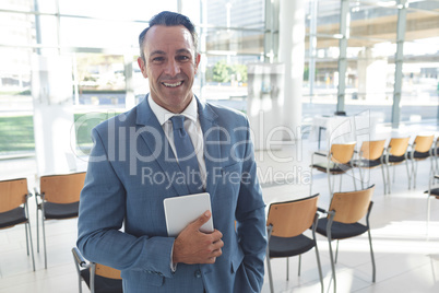 Businessman standing in conference room while holding digital tablet