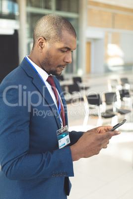 African-american male executive standing in conference room typing on smartphone