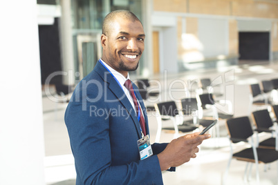 African-american male executive standing in conference room with smartphone