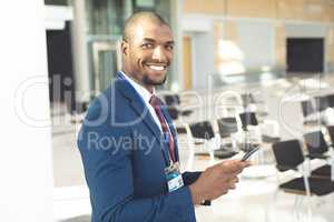 African-american male executive standing in conference room with smartphone