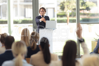 Mature Caucasian male executive doing speech in conference room, answering question