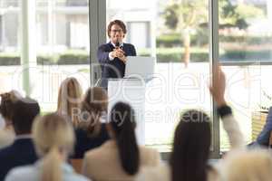 Mature Caucasian male executive doing speech in conference room, answering question