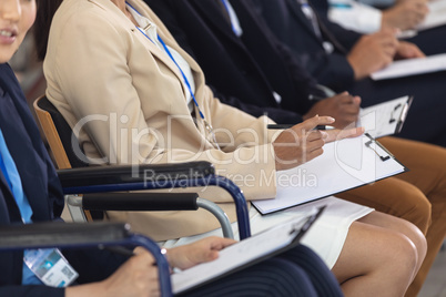 Businesswomen sitting while listening to speech in conference room