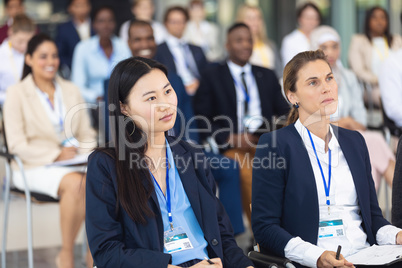 Business people sitting on chairs while listening to speech