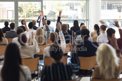 Mature businesswoman doing speech and answering questions in conference room