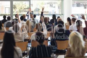 Mature businesswoman doing speech and answering questions in conference room