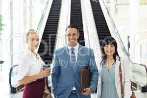 Diverse business people standing in front of escalators in modern office