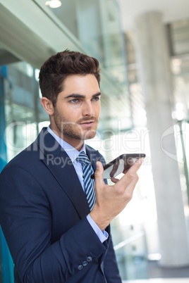 Young Caucasian businessman speaking on mobile phone while standing in modern office